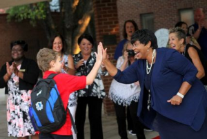 Head of School, Rebbie Evans greats students on red carpet with a high-five!  