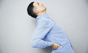 Man having a back pain over gray background