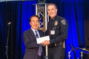 Photos: (top) Irving Police Chief Larry Boyd receives the NEC donation check from NEC President and CEO Shin Takahashi.