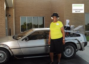 Sister Tarpley standing in front of the Delorean Time Machine at the Grand Opening of the first major luxury, six floors hotel (the Courtyard Marriott) in Carrollton, Texas through the major effort of former mayor, the honorable Ron Branson, picture by Bruce Wolpert, This Green Screen.           