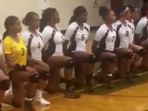 DeSoto High School girls volleyball team takes a kneeling stance during the national anthem at a recent game